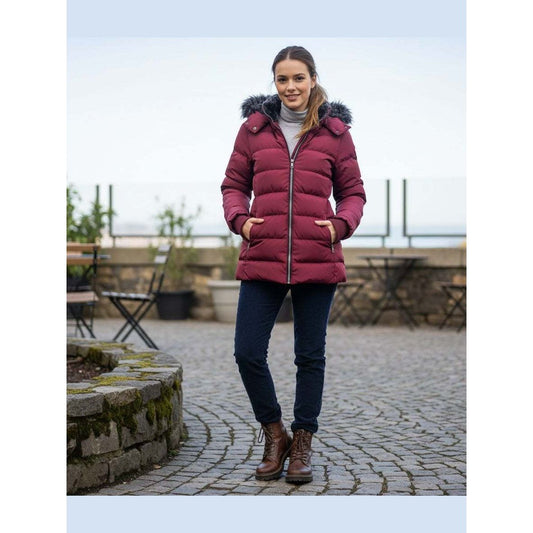Woman wearing a red puffer jacket standing outdoors on a stone path.