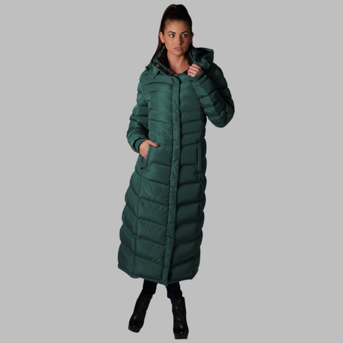 Full-Length Puffer Coat in dark green with horizontal quilting, full-length hooded design, and zippered pockets worn by a woman