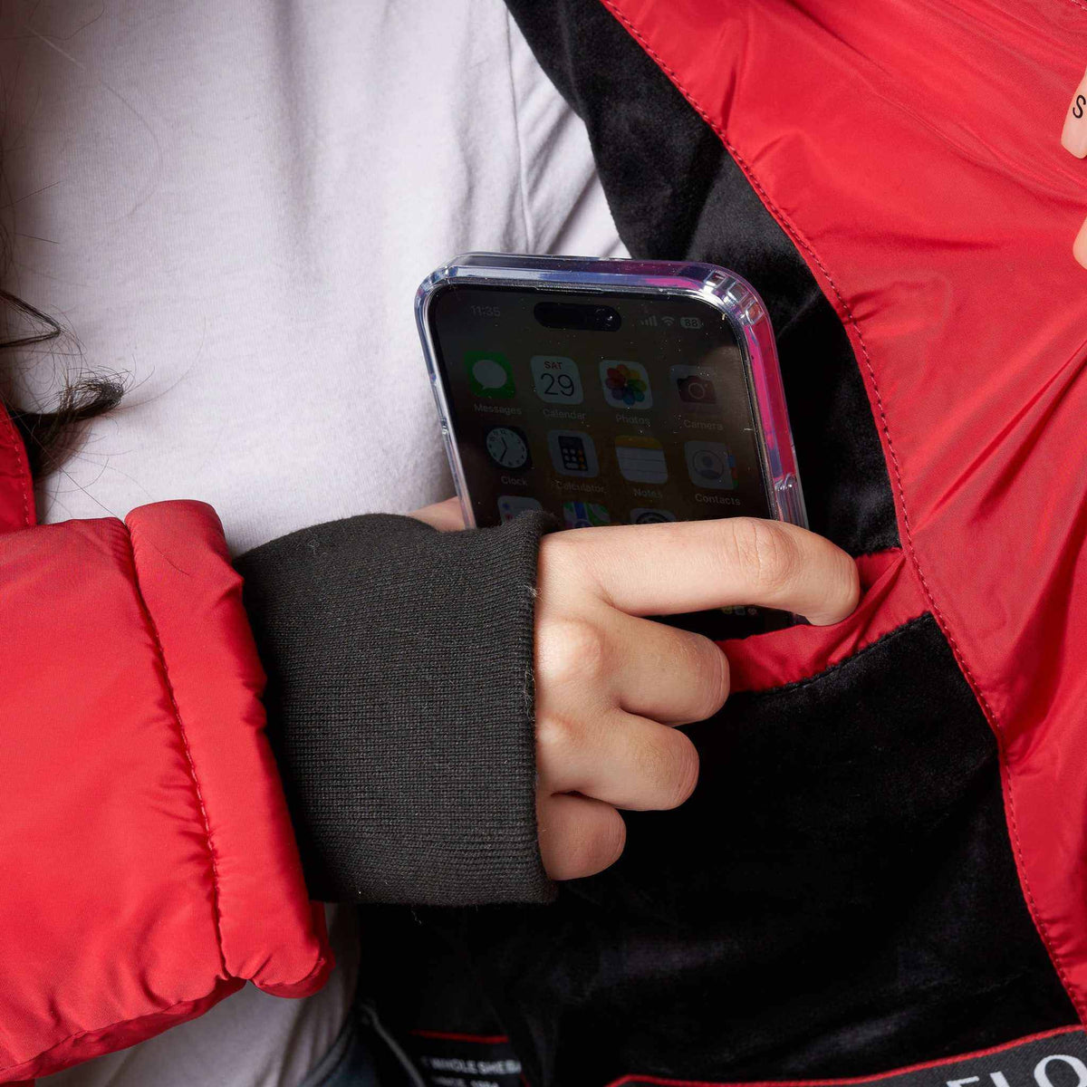 Full-Length Puffer Coat in red and black polyester with fleece lining, featuring a zippered pocket holding a smartphone and knit rib inner cuff with thumbhole